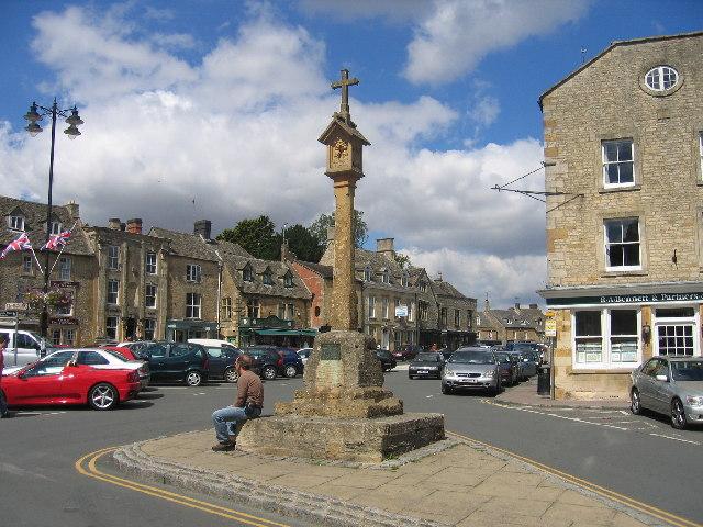 The medieval stepped market cross on the Market Square in Stow-on-the-Wold, with Cotswold-stone shops behind